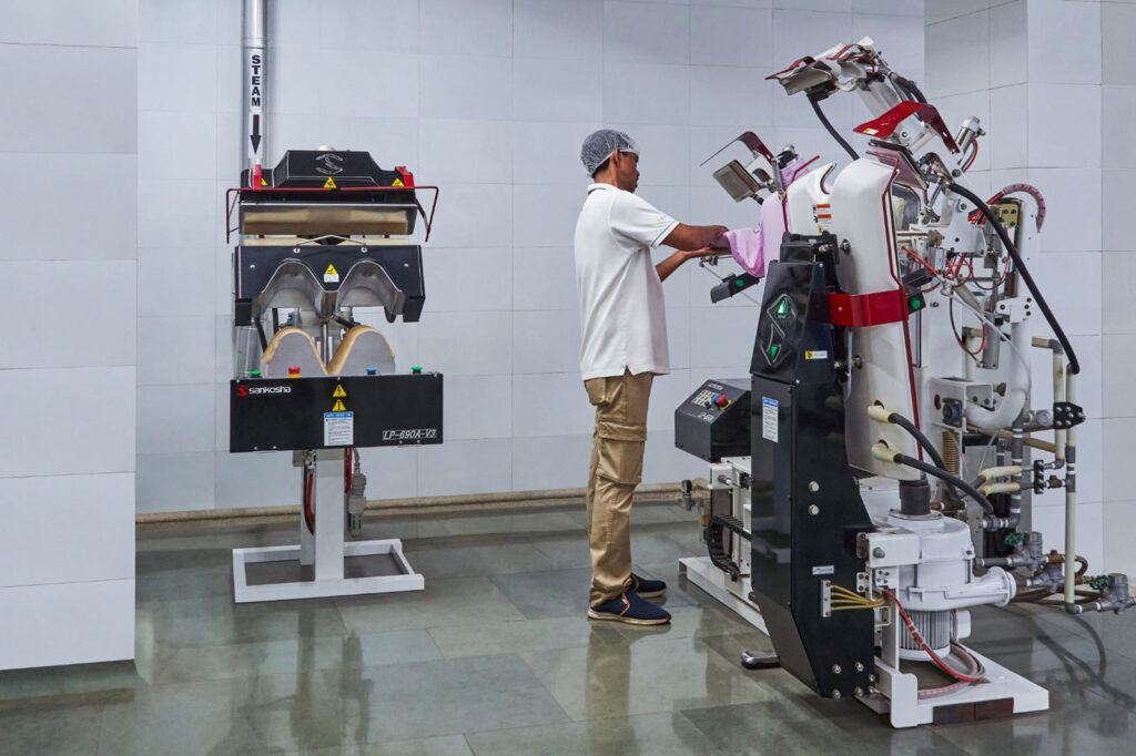 Staff using advanced garment finishing machines at Bianca's dry cleaning facility in Mumbai.