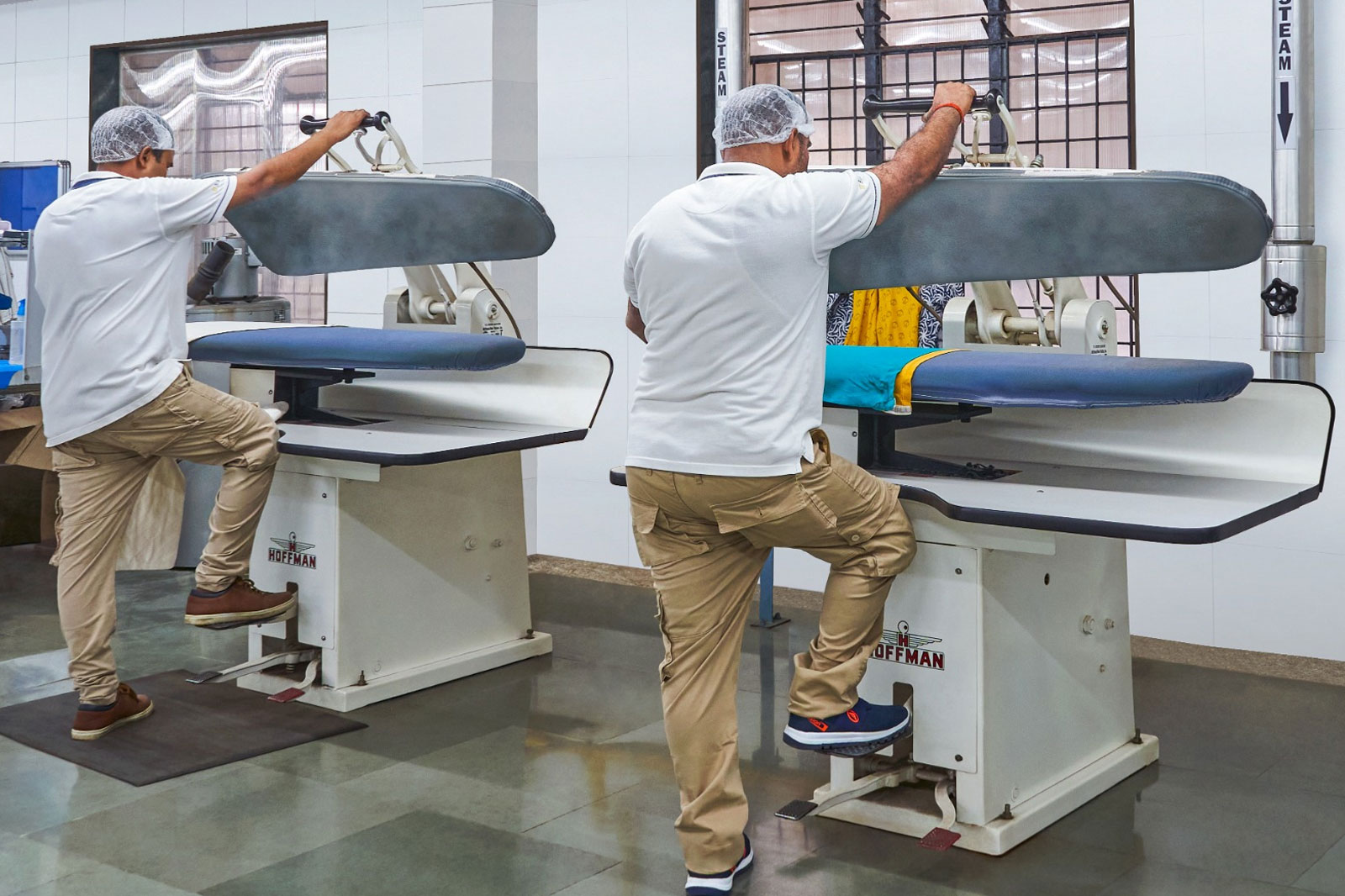 Technicians using advanced steam presses at Bianca’s dry cleaning facility in Mumbai.
