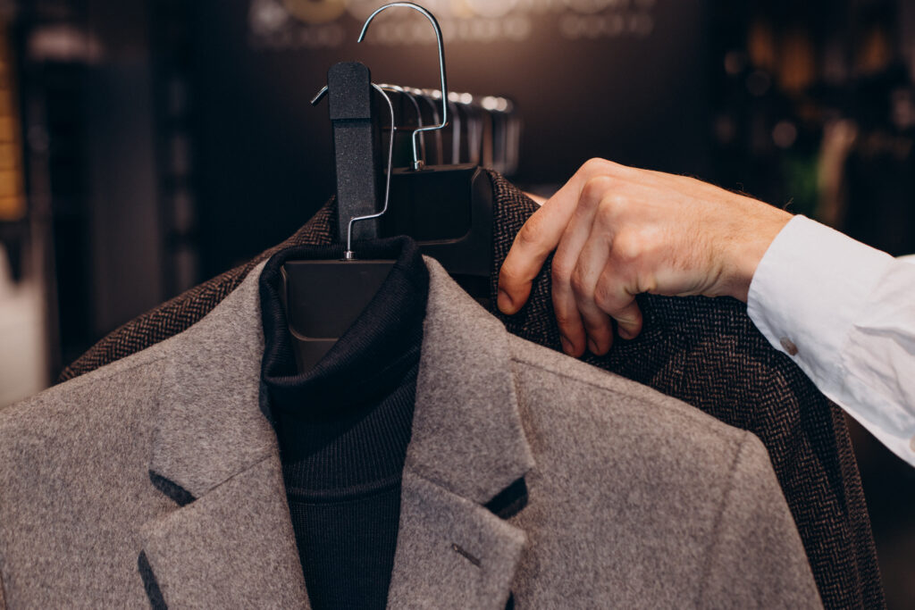 Man holding suits on hangers – expert dry cleaning advice for suits in Mumbai.