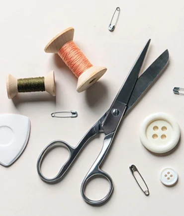 Sewing scissors, threads and buttons arranged for clothing repair and alteration