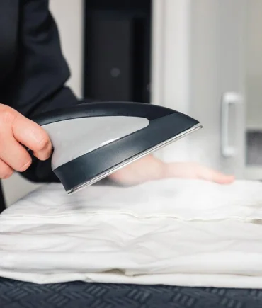 Steam iron pressing a white garment to remove wrinkles and creases